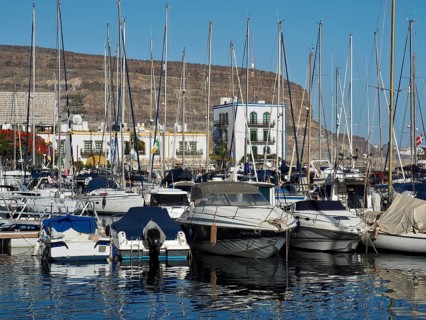 Full harbor with yachts and masts in the foreground and mountains in the background, Puerto de
