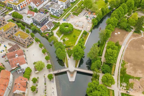 Urban aerial view with river and buildings surrounded by green spaces, European market and garden