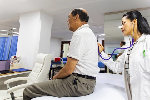 A doctor is using a stethoscope to examine a patient in a Latin hospital, highlighting the
