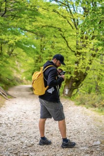 A young father placing the newborn child well in the backpack on a path in the forest heading to