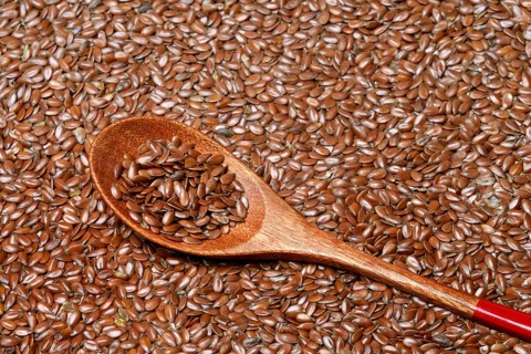 Linseed with wooden spoon, seeds of the common flax (Linum usitatissimum)