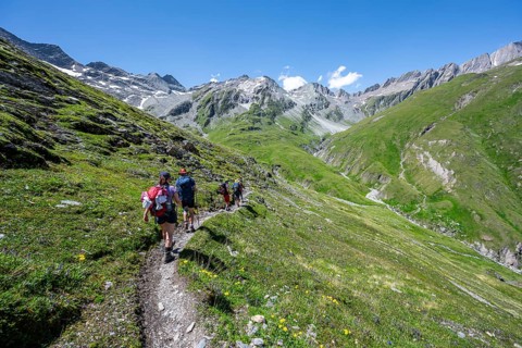 Three mountaineers on a hiking trail, view of rocky mountain peaks in the Karbach valley with