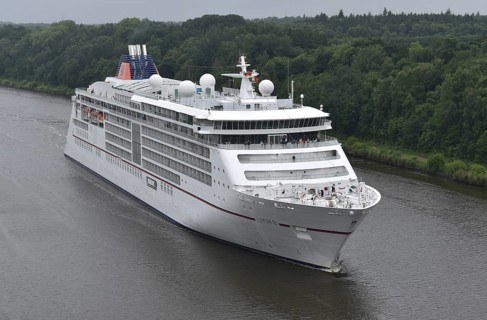 A large cruise ship sails on a wooded river under cloudy skies, cruise ship EUROPA 2 sails through