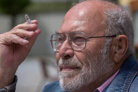 Portrait of a smoking gentleman with beard and hearing aid in ear, Bavaria, Germany