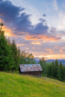 View across a meadow to a hut in the mountains at sunset, Gol, Halligdal, Buskerud, Norway