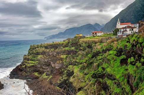 Steep coast, rocky beach and Atlantic Ocean in rainy weather, church, Seixal, Madeira, Portugal