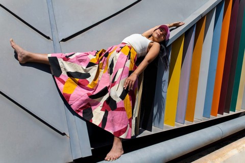 A woman in a vibrant, colorful outfit contrasts strikingly with the sleek, geometric lines of