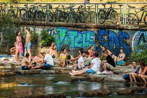 Young people sitting by and in the river, bathing in the city, heat, heat wave, climate change,