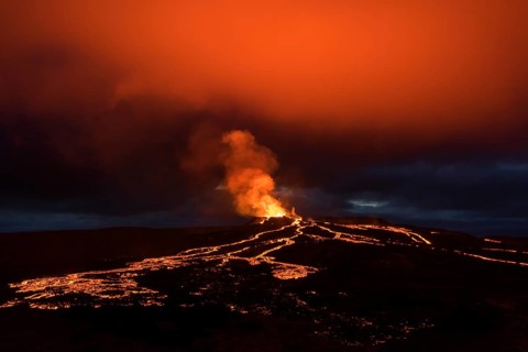 Lava spurting from crater and reddish reflection on cloud, lava flows, erupting volcano,