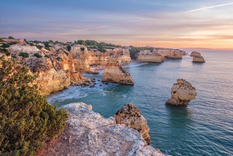 Sunrise view of Praia da Marinha beach in Algarve, Portugal, with a limestone sea arch, Atlantic