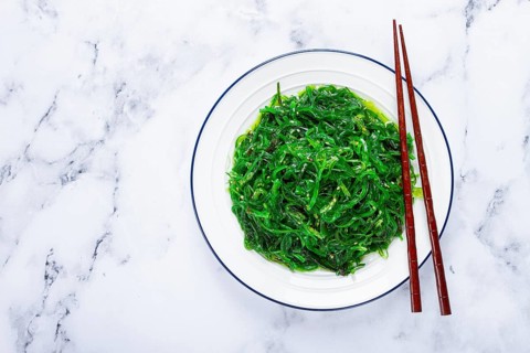Chuka salad, made from fresh seaweed, with sesame dressing, served on a white plate, with