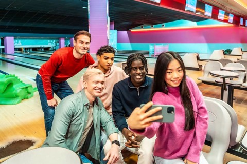 Group of young multiethnic friends taking a selfie at the bowling alley, enjoying their weekend