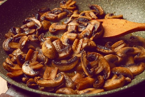 Fried mushrooms in a frying pan, with a wooden fork, homemade, no people
