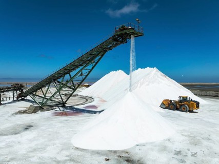 Salt heaps with conveyor belt and excavator at the Walvis Bay Salt works. Aerial view. Drone shot.