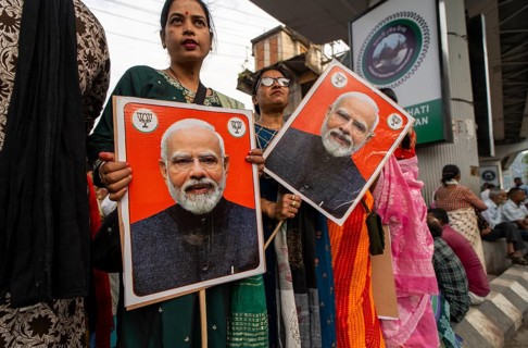 Supporters hold placards featuring Narendra Modi during a public rally of the Bharatiya Janata