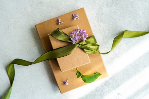 Two brown gift boxes adorned with green ribbon and purple flowers, creating an elegant presentation