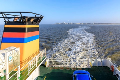 Ferry Frisia II crossing from Norderney to Norddeich Mole, in the background the silhouette of