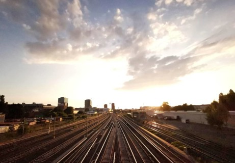 Railway tracks at sunset surrounded by buildings and a cloudy sky, Berlin