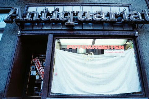 Historical photo of a neon sign second-hand bookshop above a newly opened photo shop, presumably