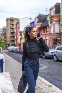 Vertical photo of a beauty african american businesswoman talking to the cellphone walking down