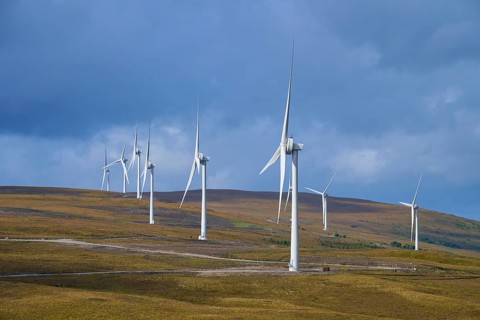 Row of wind turbines on hills under blue sky with some clouds, Lairg, Scotland, United Kingdom,