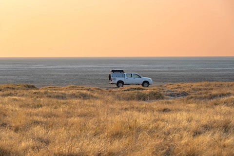 Off-road vehicle on the salt pan, at sunrise, Kubu Island (Lekubu), Sowa Pan, Makgadikgadi salt