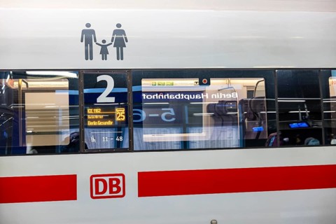 Berlin Central Station. The station board is reflected in the window. Deutsche Bahn AG logo. Family