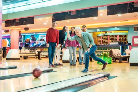 Multiethnic friends enjoying a lively bowling game in a vibrant, well lit alley, sharing laughter