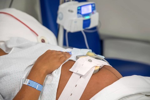 Cropped, unrecognizable woman in hospital bed, ready for childbirth. The scene captures the