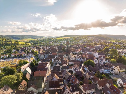Malebic urban aerial view at sunset with numerous roofs, a church and surrounding hills, Weil der