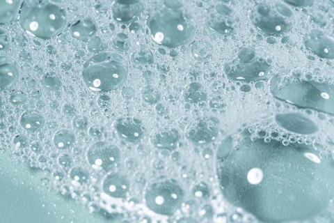 Top view of transparent gel bubbles forming intricate patterns on a laboratory glass surface. The