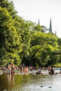 Young people sitting by and in the river, bathing in the city, heat, heat wave, climate change,