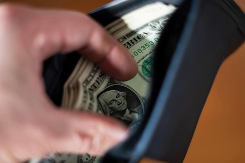 A blurred hand places or taking folded US dollar bills, with George Washington's portrait visible,