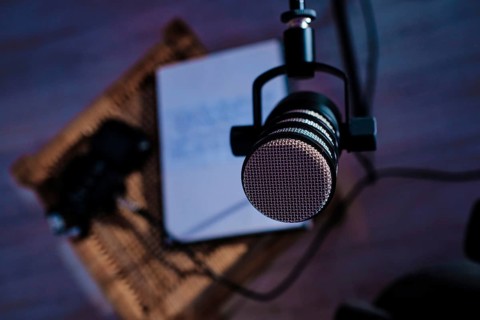 A focused close up of a microphone suspended in a bedroom, with a notebook in the blurred