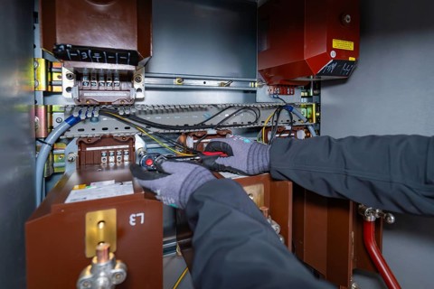 A technician works inside a switch box and uses tools for maintenance, switch cabinet construction,
