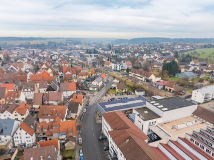 Spacious town view with red roofs and a meandering main street under an overcast sky, Meßkirch,
