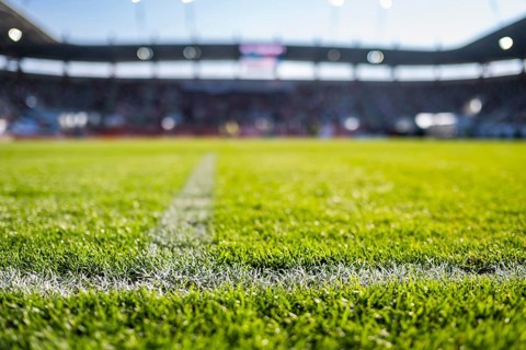 Close-up low-angle view of a white chalk boundary line on a vibrant green soccer pitch with a
