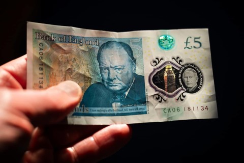 Close-up of a Bank of England five pound note featuring Sir Winston Churchill and the portrait of