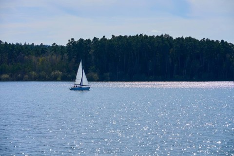 A sailboat on a quiet, sparkling lake, surrounded by the edge of a forest, Ramsberg, Großer