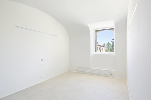 A bright, minimalist empty room of hospital with a single window. Natural light floods the space,