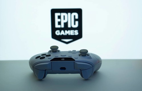 Game controller in front of Epic Games logo on a plain white background