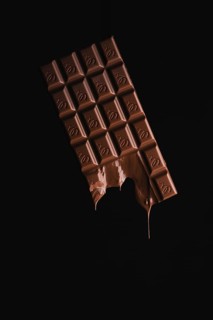 A floating, partially melted chocolate bar on a black background