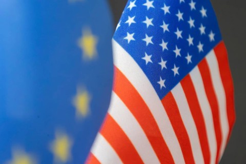 Flag of the USA, blurred in the foreground the flag of the European Union