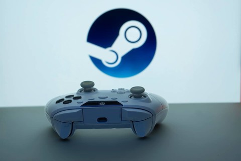 Game controller in front of Steam logo on a white background