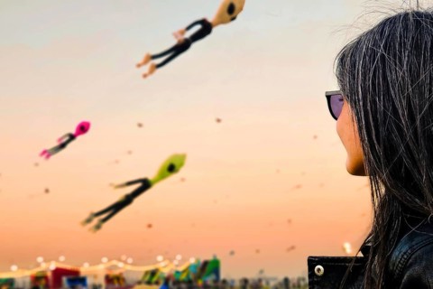 Doha, Qatar - 22nd january, 2026:woman spectator watch colorful giant kites flying above public
