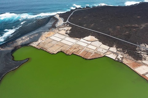 Aerial view of the vibrant green saltwater lagoon and geometric salt pans at Los Salares de