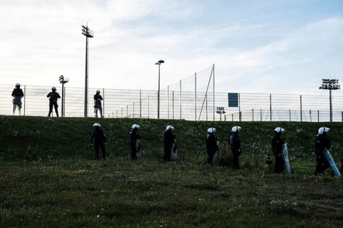Silhouettes of policemen standing next to the football field (inscription in Polish Police) in