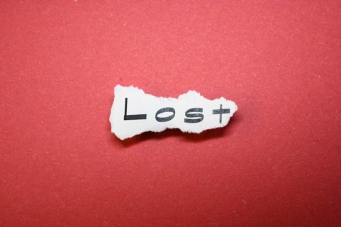 The word 'Lost' on torn paper on a red background symbolises forlornness