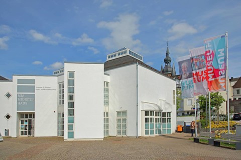 Modern white building with flags and inscription museum, banner, church tower, city library, Mia