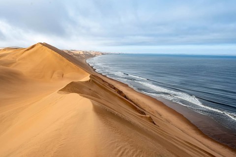 Sand dunes and sea in morning light, Atlantic coast and Namib desert, impressive desert landscape,